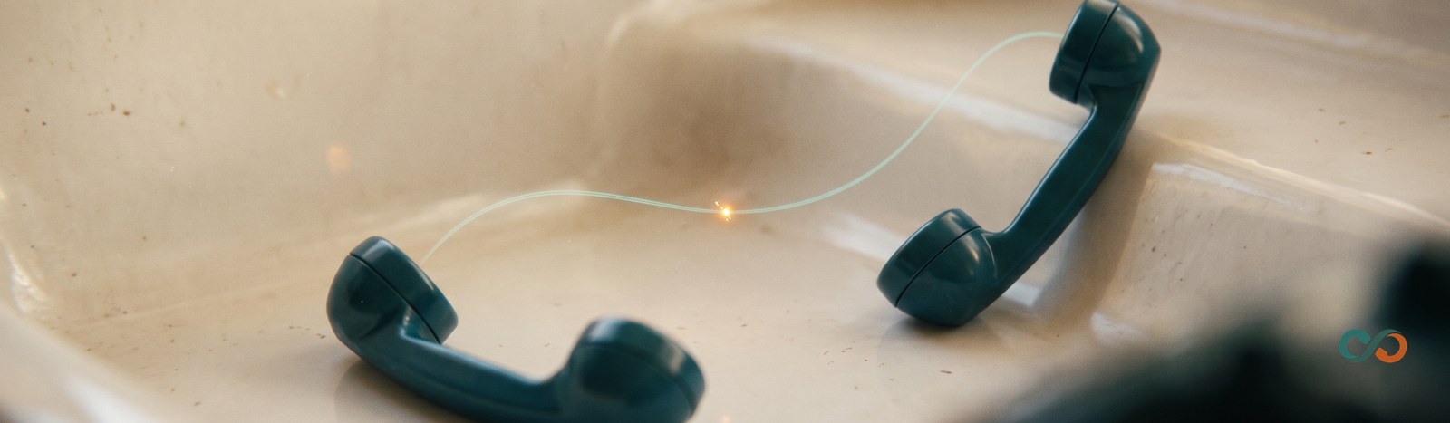 AI receptionist human handoff: two telephone handsets linked by a thread of light